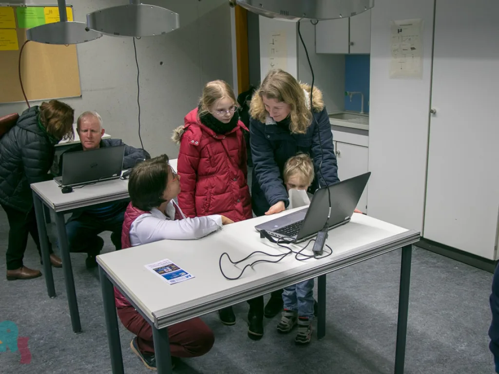 Besucher stehen an Laptops im Computerraum.
